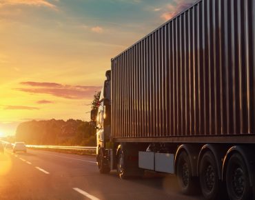 Scenic front view big long heavy semi-treailer truck with sea shipping container driving highway